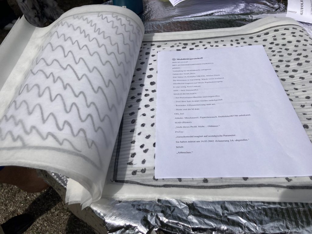 Aufgeschlagene Mappe mit Textdokument und Musterpapier auf einem Tisch mit silberner Unterlage