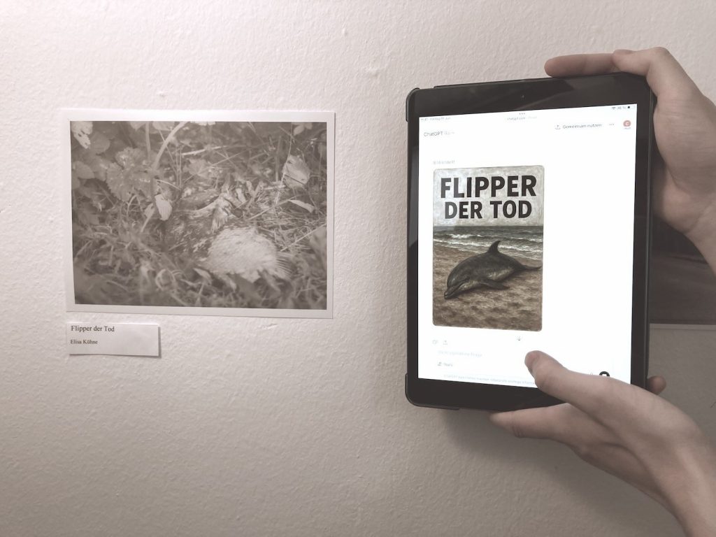 Wand mit Schwarzweißfoto eines toten Fisches mit Beschriftung 'Flipper der Tod' und daneben Tablet, das ein digitales Bild mit Titel 'FLIPPER DER TOD' und einem gestrandeten Delfin als von KI generiertem Bild zeigt